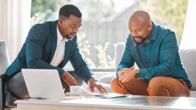 A broker is explaining a contract while speaking with a man in his house, possibly for a meeting to seek advice.