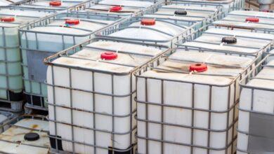 Rows of intermediate bulk containers (IBCs) stacked on top of each other. Metal cage covers each of the containers.